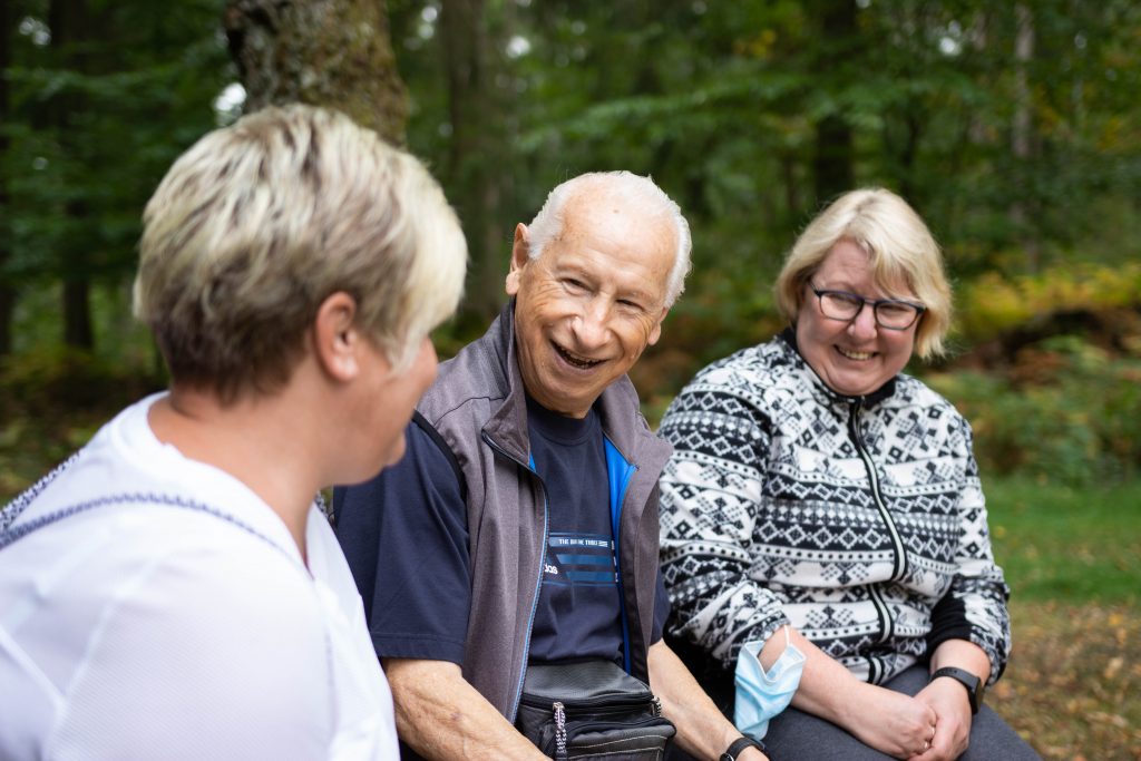 Drei fröhliche Personen nebeneinander, zwei davon Senioren